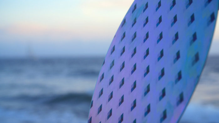 Multicolor singular disk with a cube pattern on it. Out of focus ocean and horizon background.