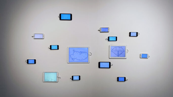 Grouping of spaced out smartphones and tablets with line drawings on screens hung on a white wall.