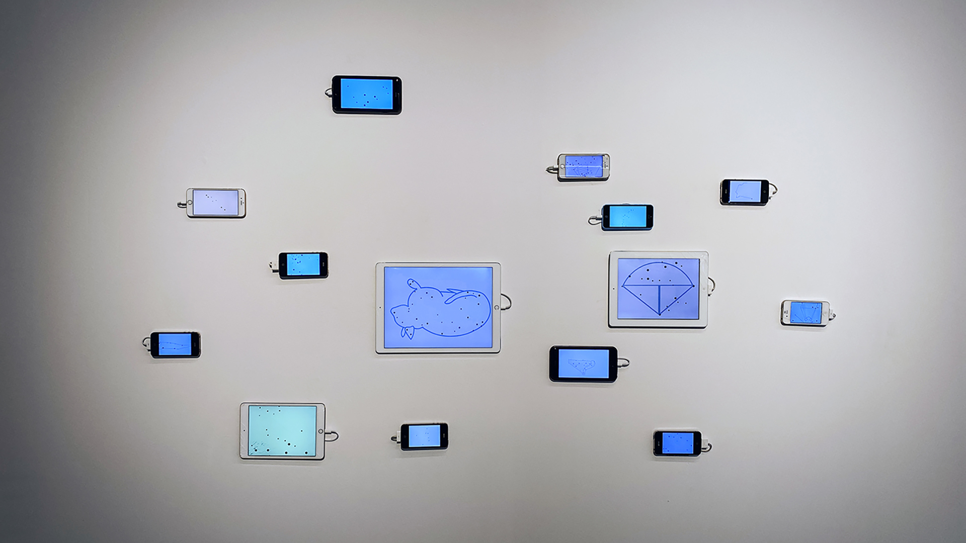 Grouping of spaced out smartphones and tablets with line drawings on screens hung on a white wall.