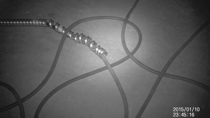 Black and white photo of cables intersecting with one another on the concrete floor. The lower right corner displays the text: 2015/01/10 and 23:45:16 right below it.